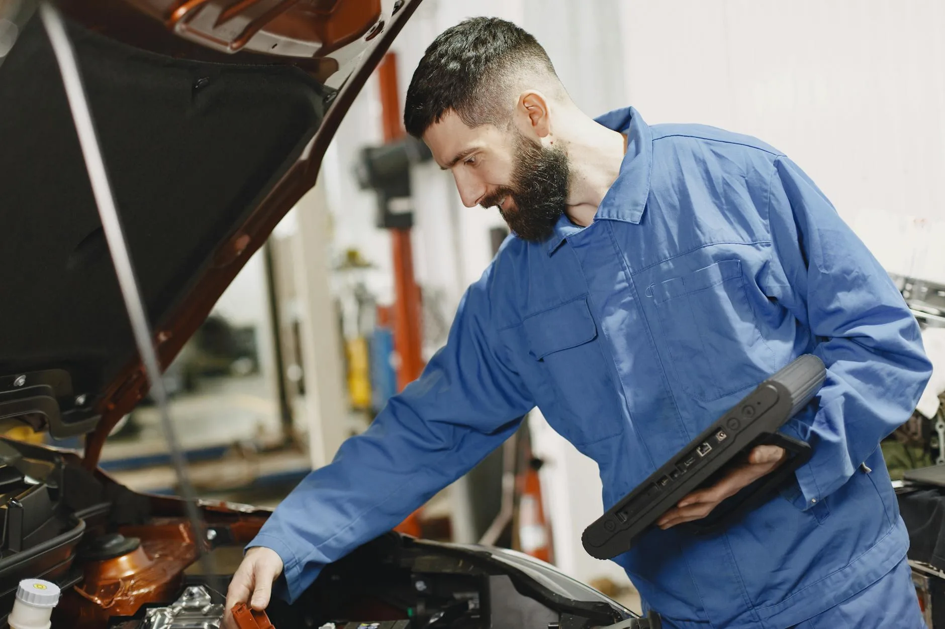Mechanik w niebieskim kombinezonie sprawdza silnik używanego Nissana