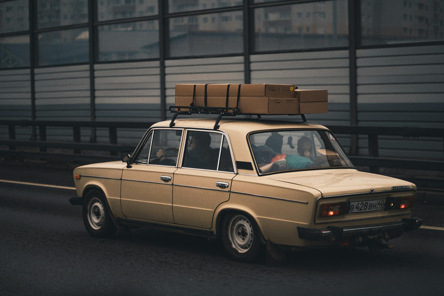 Beżowy sedan Changan z bagażem na autostradzie w kierunku miasta