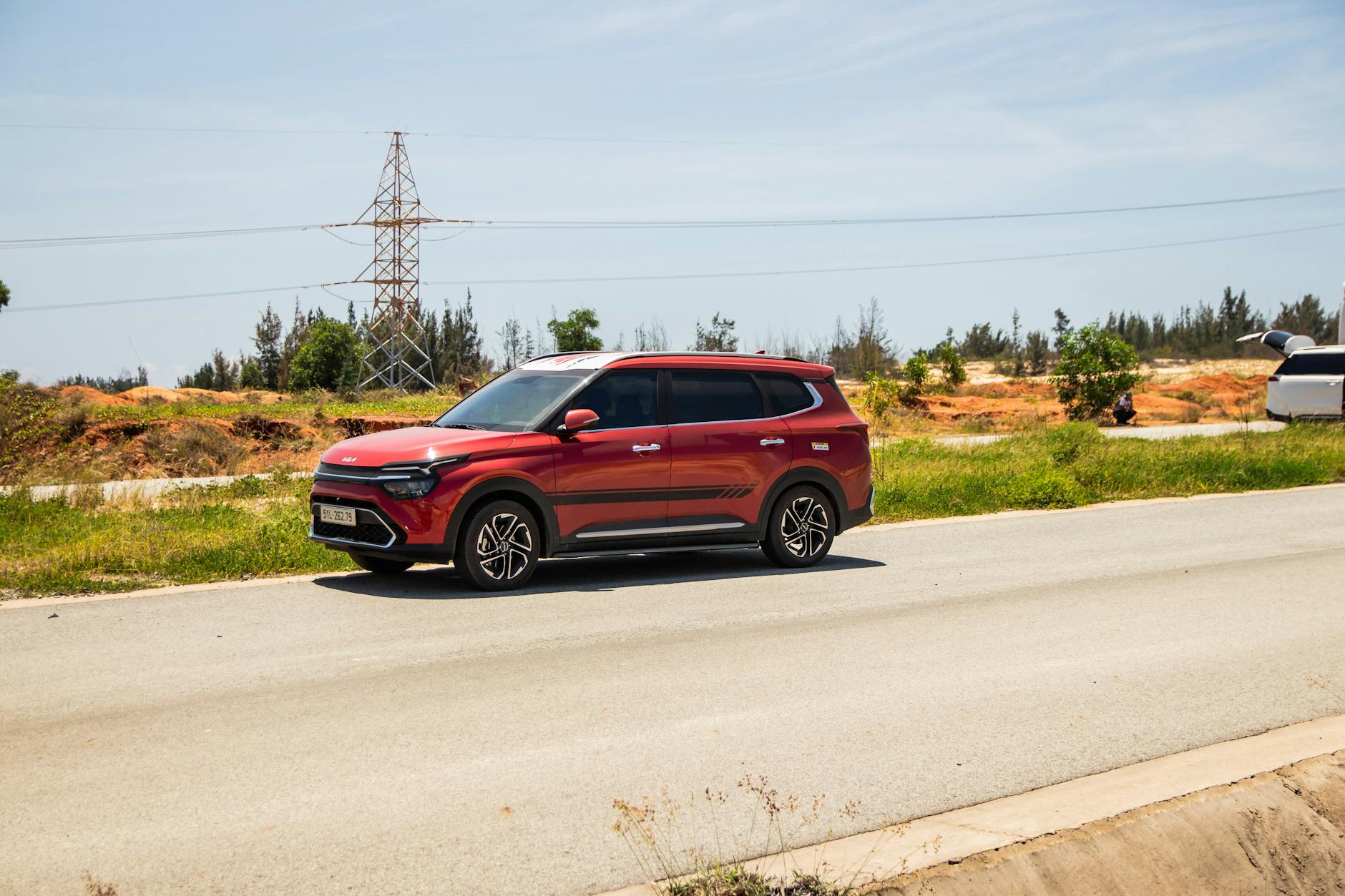 Czerwony SUV Changan jedzie słoneczną drogą wśród zieleni w Wietnamie