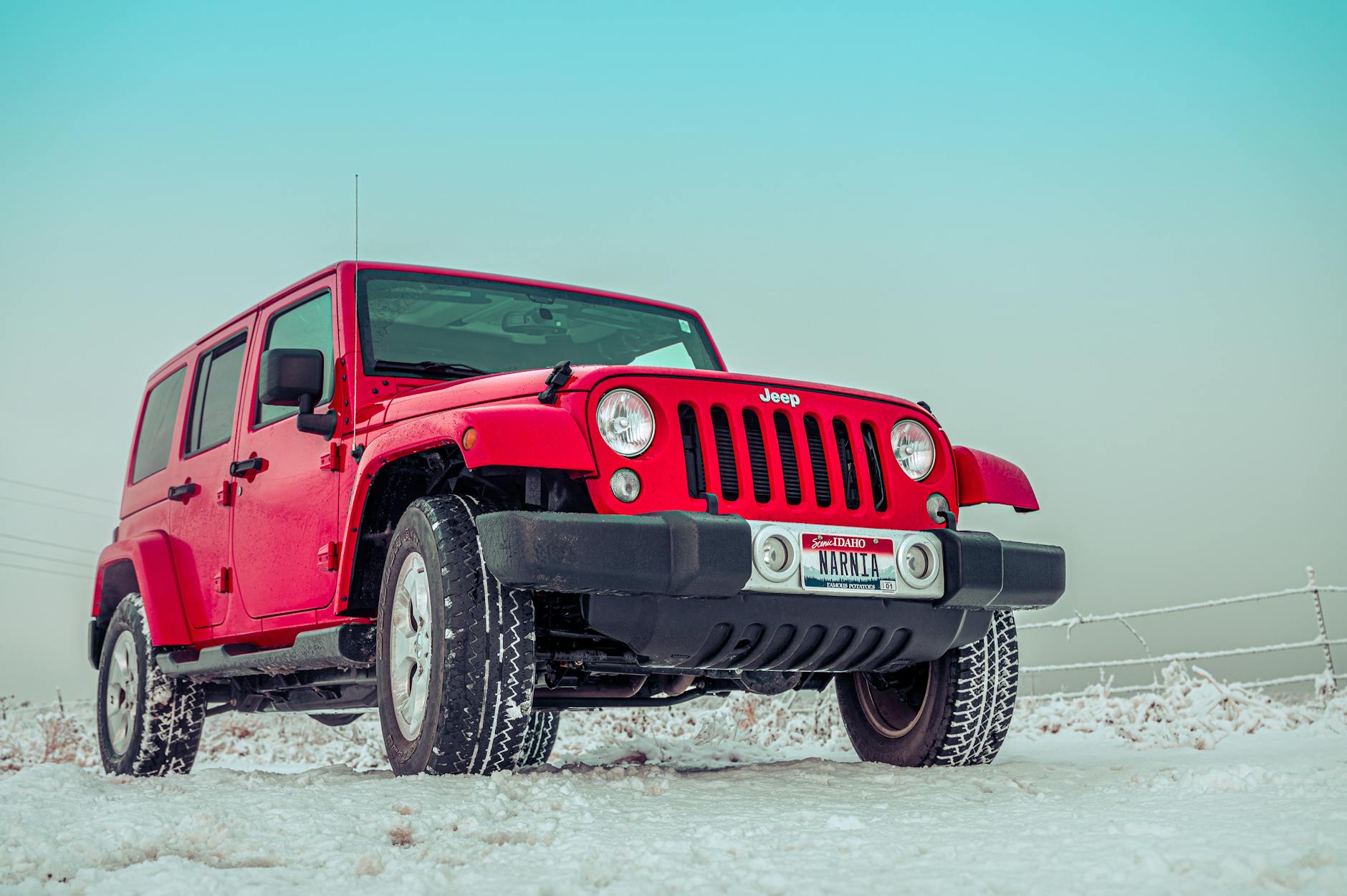 Czerwony SUV Jeep zaparkowany na ośnieżonym polu zimą