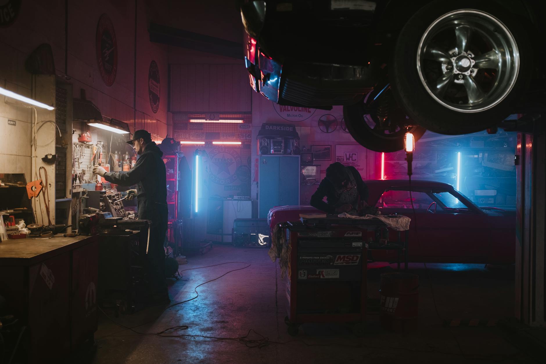 Mechanicy naprawiają Teslę w neonowo oświetlonym warsztacie
