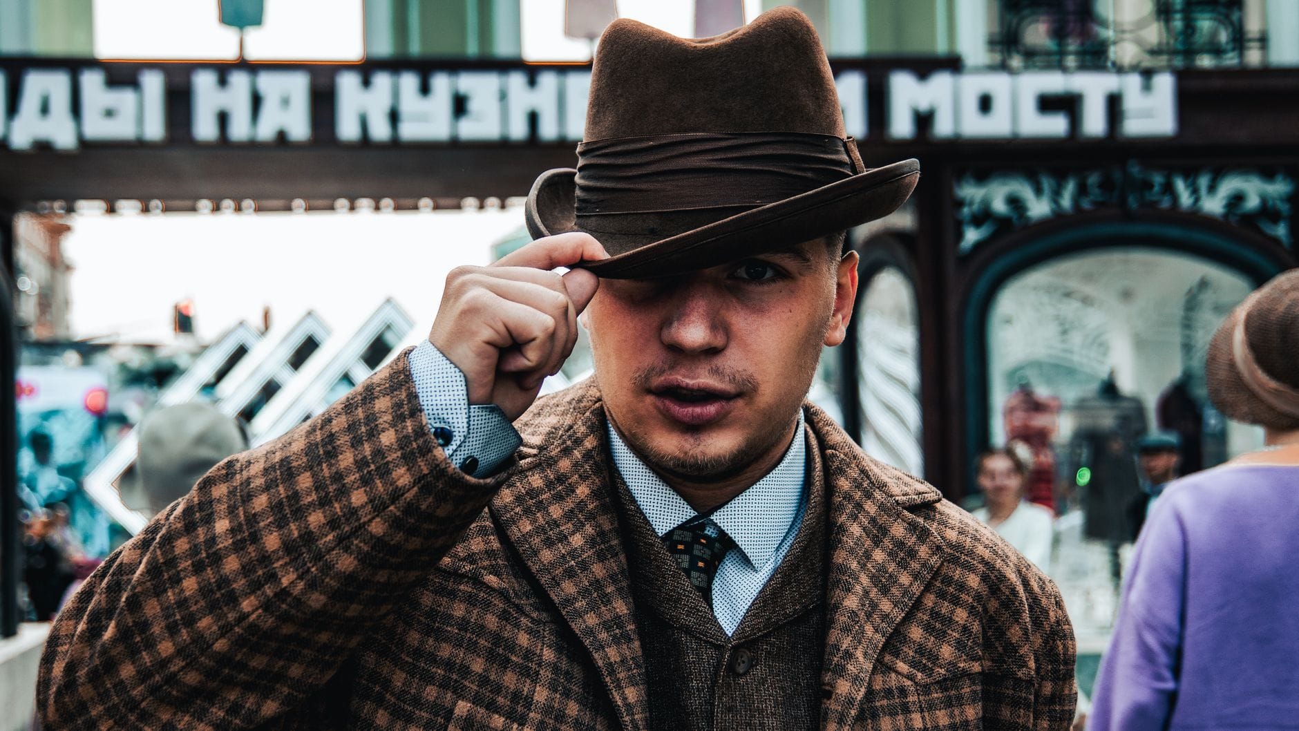 Elegancki mężczyzna w brązowym płaszczu i fedora na miejskiej ulicy Elegancki mężczyzna w brązowym płaszczu i fedora na miejskiej ulicy