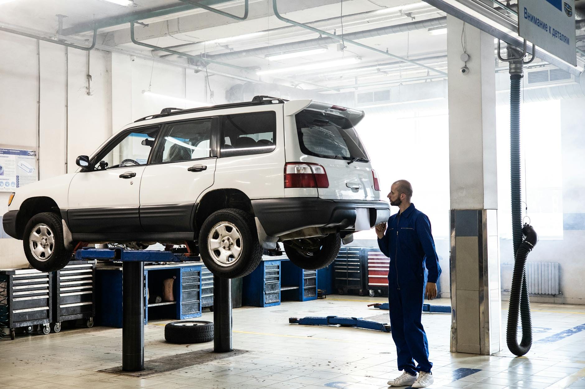 Mechanik sprawdza podniesionego SUV-a w nowoczesnym warsztacie Mechanik sprawdza podniesionego SUV-a w nowoczesnym warsztacie